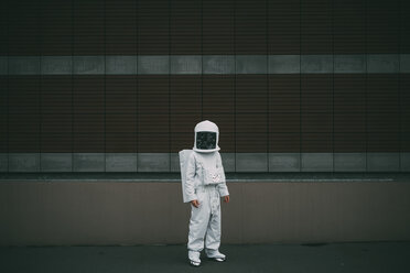 Astronaut standing against striped concrete wall - CUF50717