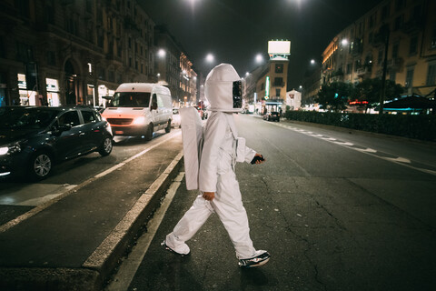 Astronaut überquert Straße bei Nacht, lizenzfreies Stockfoto