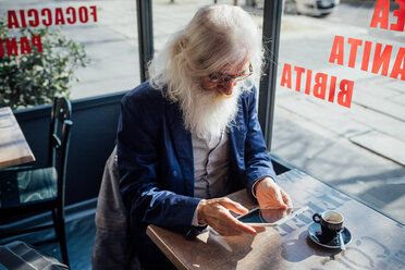 Älterer Geschäftsmann mit digitalem Tablet in einem Café, Mailand, Lombardei, Italien - CUF50737