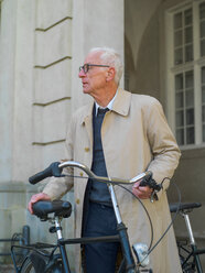 Älterer Mann im Regenmantel mit Fahrrad, Kopenhagen, Hovedstaden, Dänemark - CUF50912