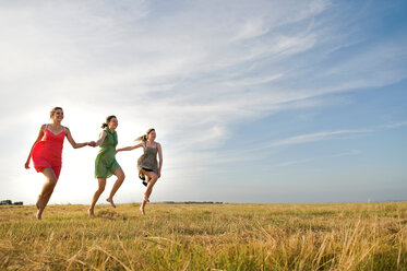 Girlfriends skipping on field, Eastbourne, East Sussex, United Kingdom - CUF51034