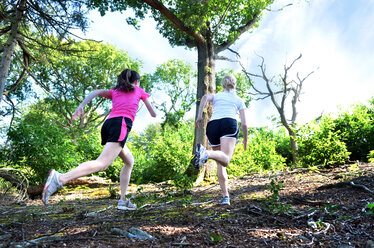 Girlfriends running in forest, Tunbridge Wells, Kent, Vereinigtes Königreich - CUF51037