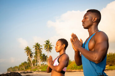 Couple practising yoga on beach - CUF51068