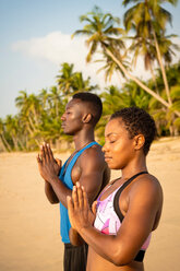 Couple practising yoga on beach - CUF51073