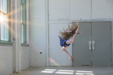 Teenager-Mädchen mit langen braunen Haaren springt mitten in der Luft im Tanzstudio - ISF21293