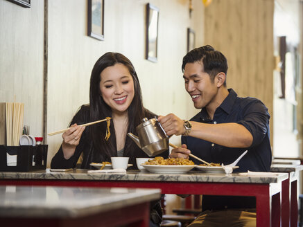 Chinesischer Mann schenkt einer Frau im Restaurant Tee ein - BLEF03057