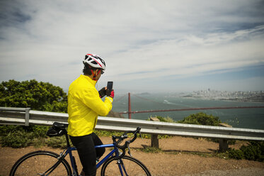 Hispanischer Mann auf dem Fahrrad, der mit seinem Handy das Hafenviertel fotografiert - BLEF03071