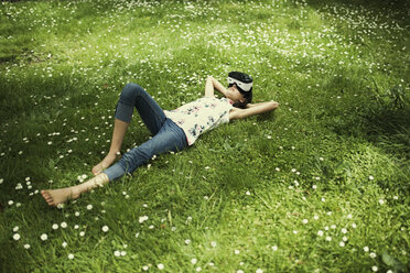 Mixed-Race-Mädchen liegt im Gras und trägt eine Virtual-Reality-Brille - BLEF03099