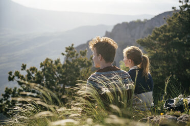 Caucasian couple sitting on hill admiring scenic view - BLEF03125