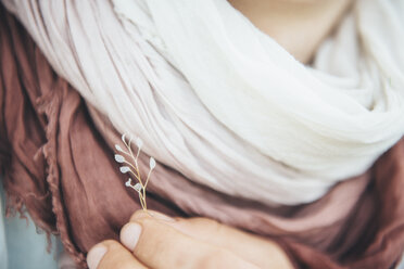 Caucasian woman holding delicate leaf near scarf - BLEF03153