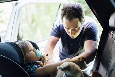 Father buckling son into car seat - BLEF03186