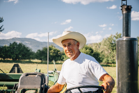 Porträt eines kaukasischen Landwirts auf einem Traktor, lizenzfreies Stockfoto