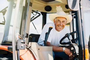 Porträt eines lächelnden kaukasischen Landwirts mit Traktor - BLEF03216