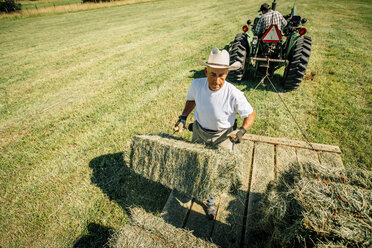 Kaukasischer Landwirt hebt einen Heuballen - BLEF03223