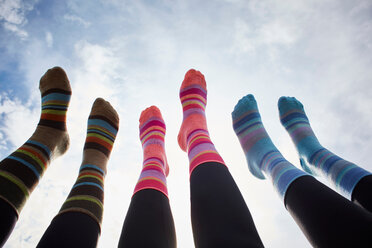 Drei junge Frauen in gestreiften Socken mit hochgelegten Beinen gegen den sonnenbeschienenen Himmel, Ausschnitt der Beine - CUF51160