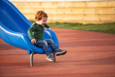 Boy playing on slide in playground - CUF51186