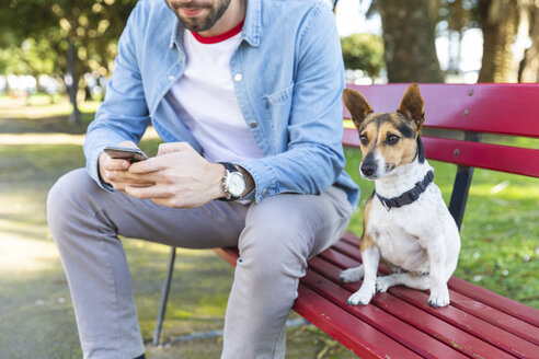 Porträt eines Hundes, der neben seinem Besitzer auf einer Parkbank sitzt - WPEF01506