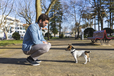 Young man teaching his dog in a park - WPEF01512