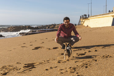 Portugal, Porto, junger Mann spielt am Strand mit seinem Hund - WPEF01520