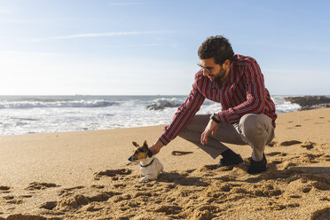 Portugal, Porto, junger Mann streichelt seinen Hund am Strand - WPEF01522