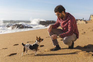 Portugal, Porto, junger Mann spielt mit seinem Hund am Strand - WPEF01523