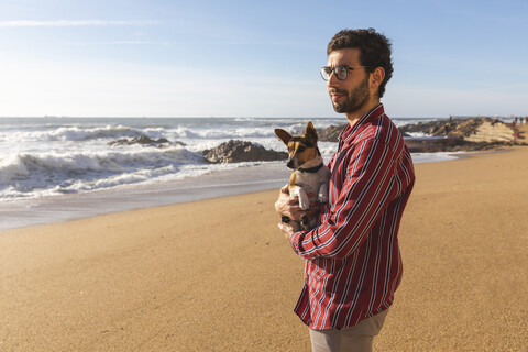 Portugal, Porto, junger Mann am Strand mit seinem Hund, lizenzfreies Stockfoto