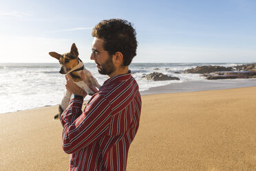 Portugal, Porto, zufriedener junger Mann am Strand mit seinem Hund - WPEF01525