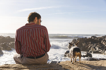 Portugal, Porto, back viwe of young man and his dog in front of the sea - WPEF01528