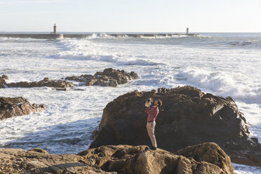 Portugal, Porto, junger Mann steht mit seinem Hund auf einem Felsen - WPEF01533