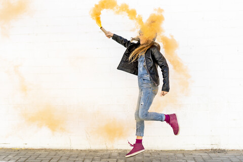 Girl with orange smoke torch jumping in the air stock photo