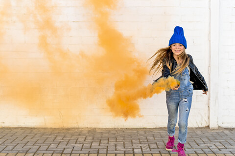 Portrait of smiling girl with orange smoke torch stock photo