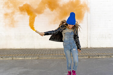 Smiling girl with orange smoke torch on the street - ERRF01280