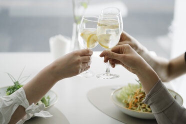 Nahaufnahme von drei Frauen, die in einem Restaurant Gläser mit Wasser anstoßen - AHSF00352