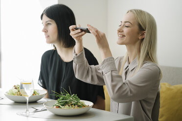 Junge Frau, die ein Handyfoto von einem Salat in einem Restaurant macht - AHSF00353