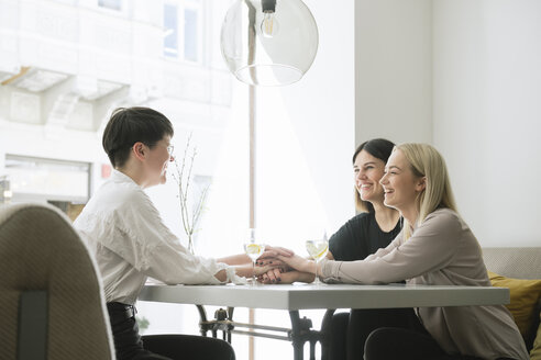 Glückliche Freunde, die sich in einem Restaurant die Hände reichen - AHSF00370