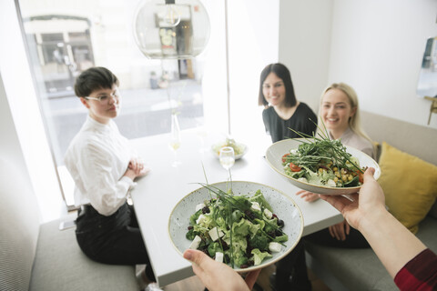 Waiter serving salad to friends in a restaurant stock photo