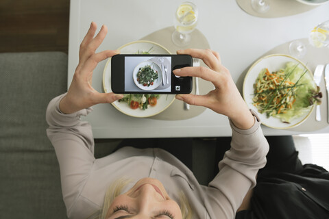 Young woman taking a cell phone picture of a salad in a restaurant stock photo