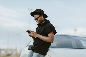 Porträt eines jungen Mannes, der mit dem Telefon eine E-Mail verschickt - OCAF00378