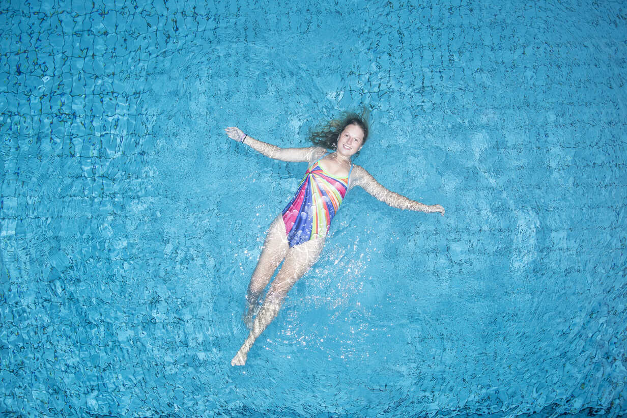 Young woman floating on water in swimming pool stock photo