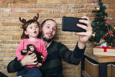 Porträt eines Vaters und seiner kleinen Tochter, die zu Weihnachten ein Selfie mit ihrem Smartphone machen - GEMF02945