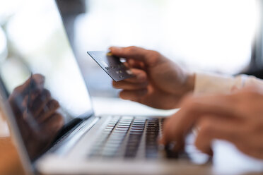 Man's hands holding credit card and typing on computer, close-up - DIGF07017