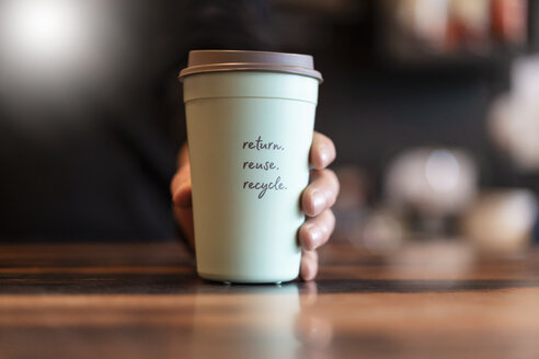 Hand holding deposit cup for Coffee to go, close-up - DIGF07030