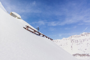 Österreich, Tirol, Galtür, Skifahrer über einem Lawinenschutz stehend - MMAF00952