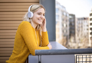 Porträt einer lächelnden jungen Frau, die mit Kopfhörern Musik hört - BFRF02009