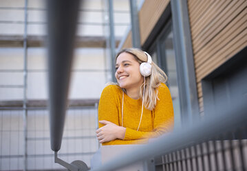 Glückliche junge Frau, die mit Kopfhörern Musik hört - BFRF02010