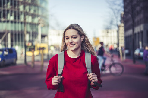 Deutschland, Berlin, Porträt einer lächelnden jungen Frau mit Rucksack in der Stadt - BFRF02019
