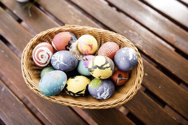 Easter eggs in basket on wooden table - KMKF00952