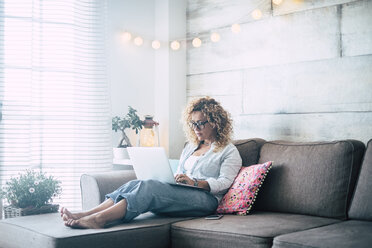 Frau benutzt Laptop auf der Couch zu Hause - SIPF01958