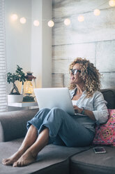 Frau benutzt Laptop auf der Couch zu Hause - SIPF01959