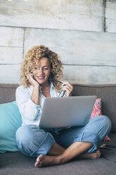 Woman using laptop on couch at home - SIPF01962